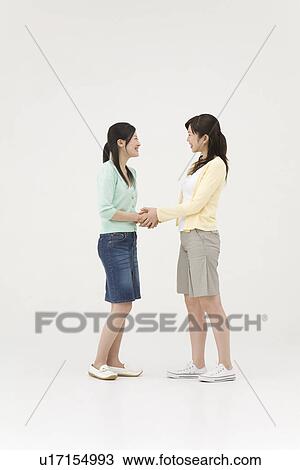 Stock Image - Two young women shaking hands. Fotosearch