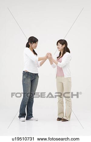 Stock Image - Two young women shaking hands. Fotosearch