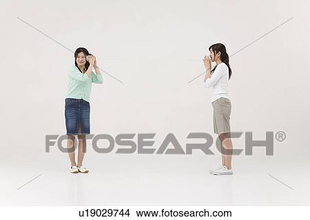 Picture - Two young women talking with string telephone. Fotosearch