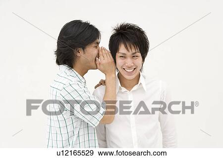Stock Photo - Young man whispering to his friend. Fotosearch