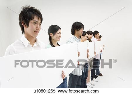 Stock Photography - Young people standing with blank message board. Fotosearch