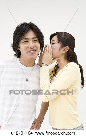 Picture - Young woman whispering to her friend. Fotosearch