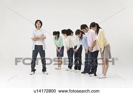 Stock Image - Group of people bowing to a young man. Fotosearch