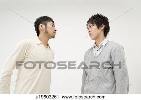 Two young men glaring at each other View Large Photo Image Stock Image - Two young men glaring at each other. Fotosearch