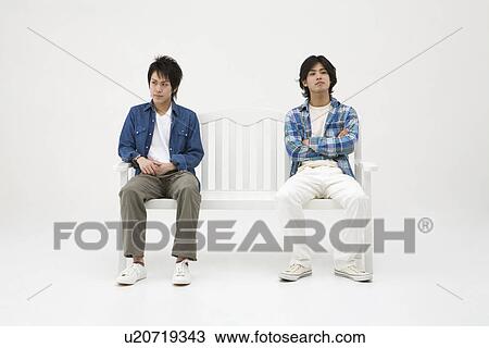 Stock Image - Two young men sitting on bench. Fotosearch