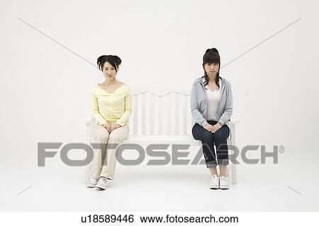 Two young women sitting on bench View Large Photo Image Stock Photograph - Two young women sitting on bench. Fotosearch