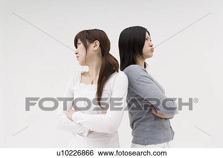 Stock Photograph - Two young women standing back to back. Fotosearch