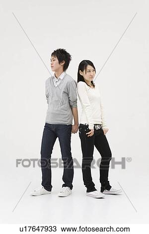 Stock Image - Young couple standing back to back. Fotosearch
