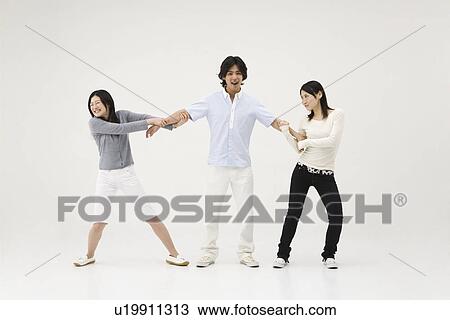 Stock Image - Young man pulled by two young women. Fotosearch