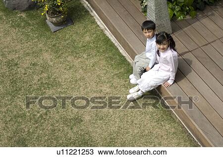 Boy and girl sitting on wooden deck View Large Photo Image Stock Image - Boy and girl sitting on wooden deck. Fotosearch