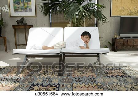 Picture - Boy lying on sofa. Fotosearch