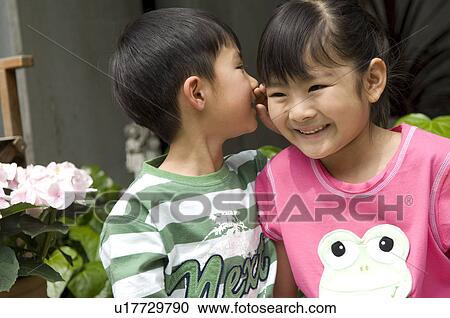 Stock Image - Boy whispering to girl. Fotosearch
