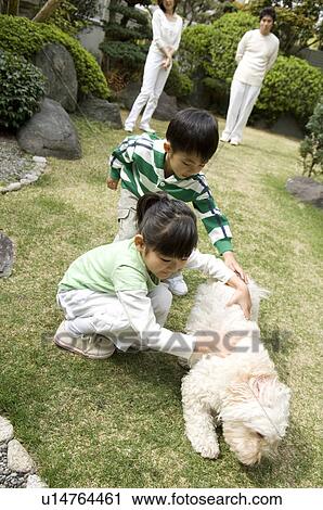 Stock Image - Children playing with dog. Fotosearch