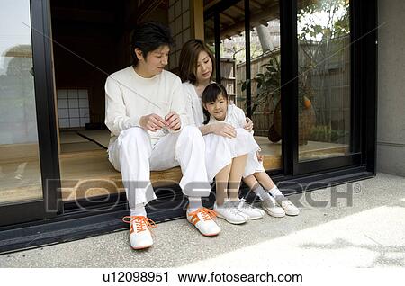 Stock Image - Family sitting on veranda. Fotosearch