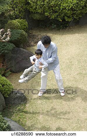 Stock Image - Father and son playing in garden. Fotosearch