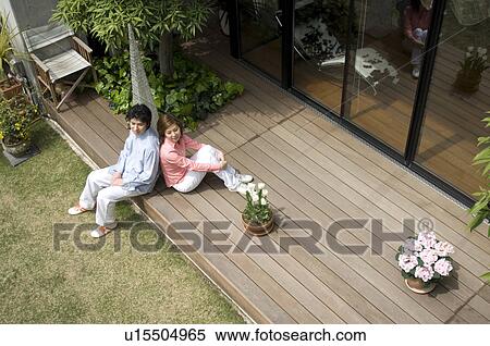 Mid adult couple sitting on wooden deck View Large Photo Image Stock Photography - Mid adult couple sitting on wooden deck. Fotosearch