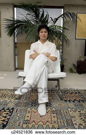 Mid adult man sitting on chair View Large Photo Image Stock Photograph - Mid adult man sitting on chair. Fotosearch