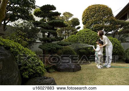 Stock Image - Mother and children watering trees. Fotosearch