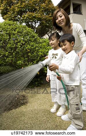 Stock Image - Mother and children watering trees. Fotosearch
