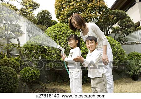 Stock Image - Mother and children watering trees. Fotosearch