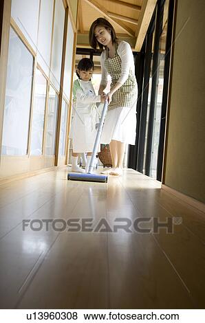 Stock Photo - Mother and daughter using vacuum cleaner. Fotosearch