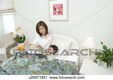Stock Image - Mother reading a book to son. Fotosearch