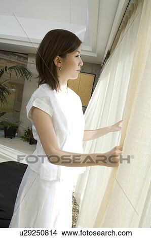 Picture - Woman looking through window. Fotosearch