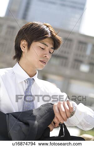 Young businessman looking at watch View Large Photo Image Picture - Young businessman looking at watch. Fotosearch