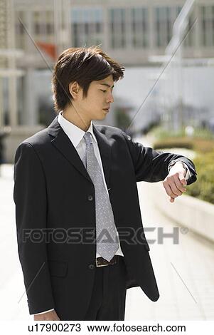 Young businessman looking at watch View Large Photo Image Stock Image - Young businessman looking at watch. Fotosearch