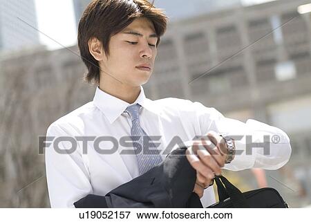 Young businessman looking at watch View Large Photo Image Stock Photo - Young businessman looking at watch. Fotosearch