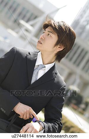 Picture - Young businessman pointing at watch. Fotosearch