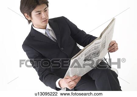 Stock Image - Young businessman reading newspaper. Fotosearch