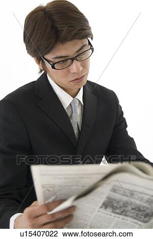 Stock Image - Young businessman reading newspaper. Fotosearch