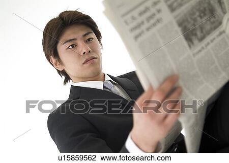 Stock Image - Young businessman reading newspaper. Fotosearch