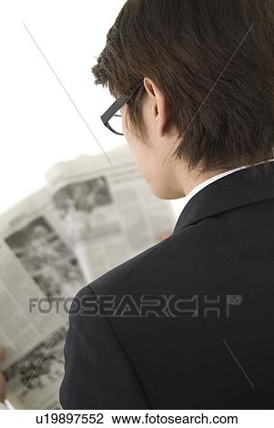 Stock Image - Young businessman reading newspaper. Fotosearch