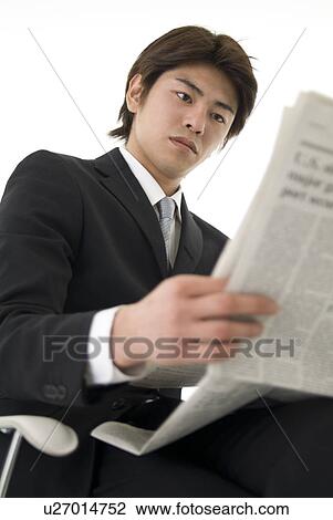 Stock Image - Young businessman reading newspaper. Fotosearch