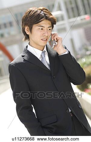Stock Photo - Young businessman using mobile phone. Fotosearch