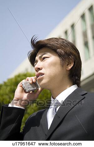 Stock Photo - Young businessman using mobile phone. Fotosearch