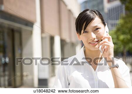 Stock Image - Young woman using mobile phone. Fotosearch