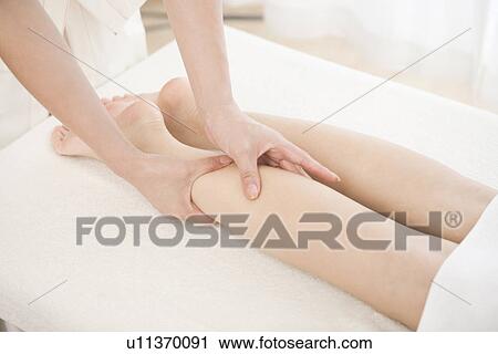 Stock Image - Massage therapist applying foot massage. Fotosearch
