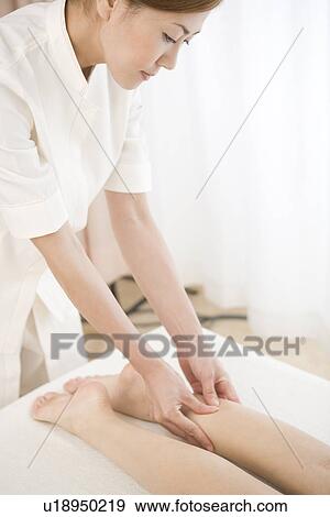 Stock Photo - Massage therapist applying foot massage. Fotosearch