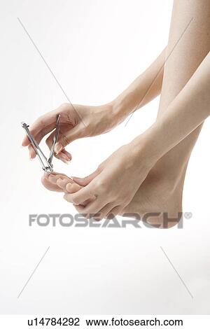 Stock Image - Young woman cutting toenails. Fotosearch