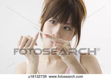 Stock Photo - Young woman filing fingernails. Fotosearch