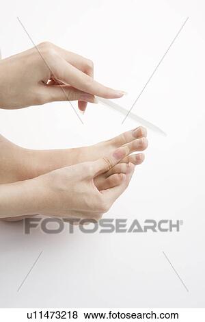 Stock Photo - Young woman filing toenails. Fotosearch
