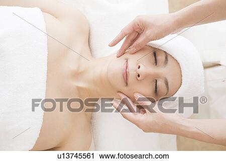 Stock Image - Young woman having facial massage. Fotosearch