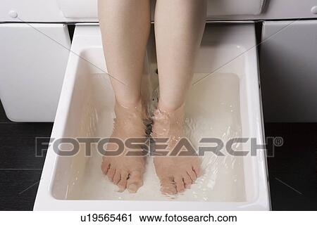 Stock Image - Young woman having foot bath. Fotosearch