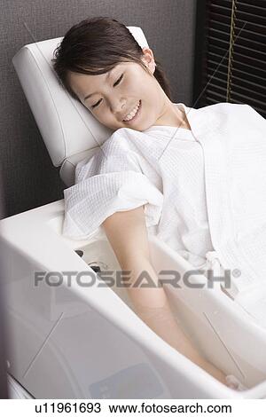 Stock Image - Young woman having hand bath. Fotosearch