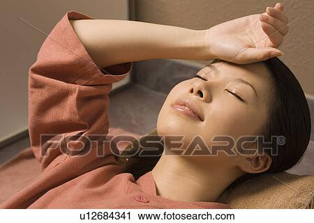Stock Image - Young woman lying at bedrock bath. Fotosearch