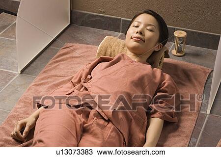 Stock Image - Young woman lying at bedrock bath. Fotosearch