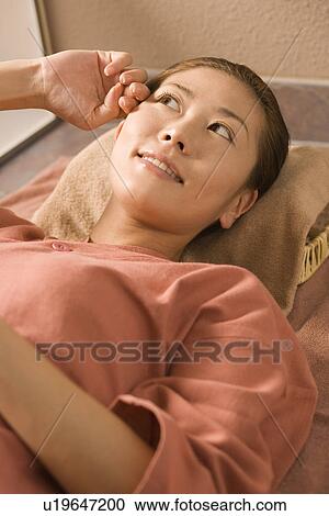 Stock Image - Young woman lying at bedrock bath. Fotosearch